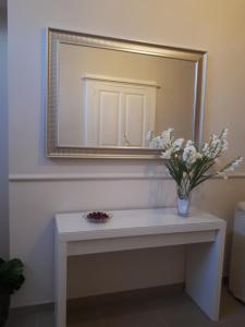 a vase of flowers on a table under a mirror at Casa ERMES 151 in Floridia