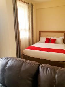 Narok的住宿－Walabi Mara Hotel，一间卧室配有一张带红色枕头的床和一张沙发
