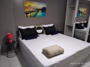 a bedroom with a large white bed with blue pillows at Estudio no West Flat Mossoró - Alto Padrão in Mossoró