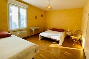 a yellow bedroom with two beds and a window at Chez Dedette in Mareuil-sur-Cher