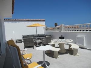 un patio con sofá, mesas y sillas en LAS ROSAS by RENTMEDANO Stunning luxury Chocolate Box villa with private heated pool & wifi, en El Médano
