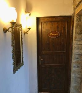 a wooden door with a sign on it next to a wall at SARI KEÇİ TAŞ OTEL in Gokceada Town