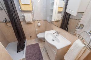 een badkamer met een wastafel, een toilet en een spiegel bij Apartments Babin - Holly in Zadar