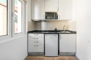 a white kitchen with a sink and a microwave at GuestReady - Palacio Garden 13 in Porto