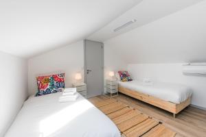 Duas camas num quarto com paredes brancas e pisos em madeira em GuestReady - Palacio Garden 13 no Porto