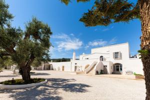 a white building with a tree in the foreground at Masseria Villa Verde in Fasano
