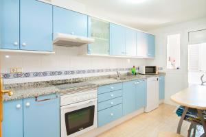 cocina azul con armarios blancos y mesa en Apartamento de 4 dormitorios a tan sólo 2,5 km de la Playa San Juan en San Juan de Alicante