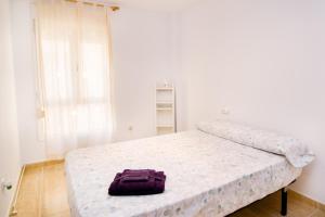 una bolsa púrpura sentada en una cama en una habitación en Apartamento de 4 dormitorios a tan sólo 2,5 km de la Playa San Juan en San Juan de Alicante