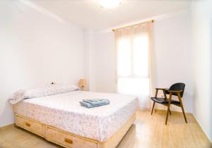 biała sypialnia z łóżkiem i krzesłem w obiekcie Apartamento de 4 dormitorios a tan sólo 2,5 km de la Playa San Juan w mieście San Juan de Alicante