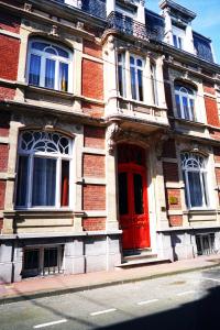 a brick building with a red door on a street at AZAL1889 in Calais