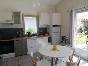 een keuken met een witte tafel en een tafel en stoelen bij Appartement proche lac et plage in Léon