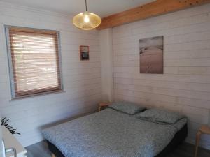 een slaapkamer met een bed in een witte kamer bij Appartement proche lac et plage in Léon