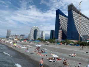 eine Gruppe von Menschen an einem Strand mit Gebäuden in der Unterkunft Orbi city Luxury suit in Batumi