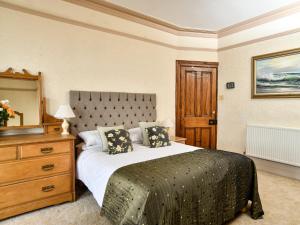 Un dormitorio con una cama con una cómoda y un espejo. en Wavecrest, en Pwllheli