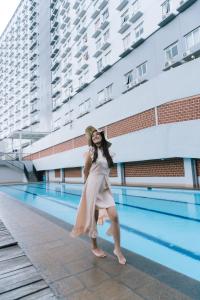 une femme en robe debout à côté d'une piscine dans l'établissement Apartmen Soekarno Hatta by C Management 4, à Malang