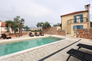 a swimming pool in front of a house at Villa Pinia in Vrbnik