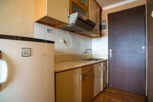a small kitchen with wooden cabinets and a door at Apartemen Soekarno Hatta by Easy Staycation 4 in Malang