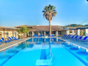 a swimming pool with blue chairs and a palm tree at Corfu SunGate Hotel in Sidari