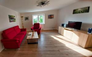 a living room with two red chairs and a tv at Ferienwohnung Schneifelsicht in Auw