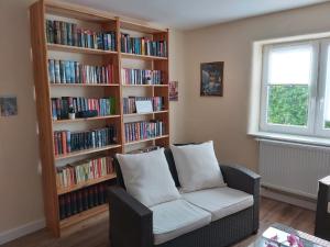 a living room with a book shelf filled with books at Ferienwohnung Schneifelsicht in Auw