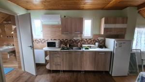 a kitchen with wooden cabinets and a white refrigerator at Maróni Ház in Zalakaros
