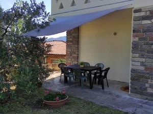 czarny stół i krzesła siedzące pod białym parasolem w obiekcie CasaDolcelago Marone Villa con Giardino Vista Lago Private Parking w mieście Marone