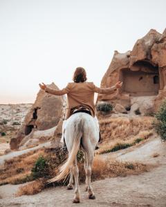 a person riding a white horse in the desert at Doda Artisanal Cave Hotel 14 Plus in Ortahisar