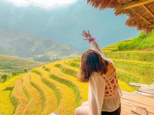 Una mujer parada en una colina con la mano en el aire en Do Gu Homestay, en Lao San Chay