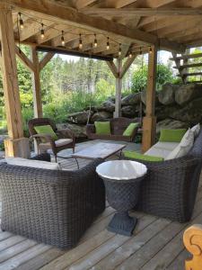 un patio con sedie e tavoli in vimini su una terrazza in legno di GÎTE SUR L'ARC EN CIEL a Saint Adrien