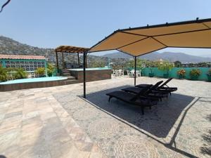 un grupo de sillas bajo una sombrilla en un patio en Hotel Tradicional Savaro SA de CV en Zihuatanejo