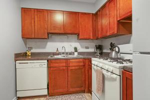 una cocina con armarios de madera y electrodomésticos blancos en Inviting 2-Bedroom Prime Chicago Apt - Oakdale 512, en Chicago