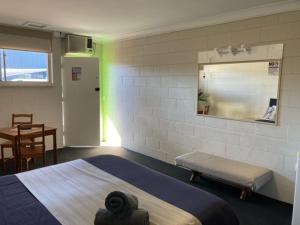 a room with a bed and a table and a mirror at Motel Wellington Wodonga in Wodonga