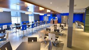 un restaurant avec des tables et des chaises et des murs bleus dans l'établissement Holiday Inn Express & Suites Vaudreuil-Dorion, an IHG Hotel, à Vaudreuil-Dorion