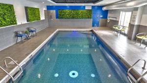 una piscina con agua azul y sillas en un edificio en Holiday Inn Express & Suites Vaudreuil-Dorion, an IHG Hotel, en Vaudreuil-Dorion