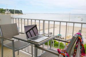 a laptop sitting on a table on a balcony overlooking the beach at Hôtel De La Plage in Saint-Pierre-Quiberon