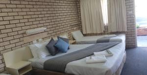 1 dormitorio con 1 cama grande y pared de ladrillo en Alfa motel, en Gilgandra