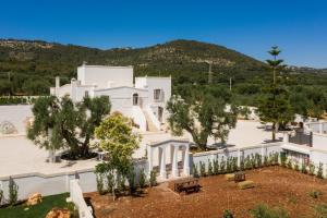 a large white building with trees and mountains in the background at Masseria Villa Verde in Fasano