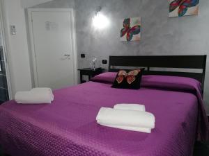 Una cama púrpura con dos toallas y dos zapatos. en B&B Villa Molinari, en Campagna