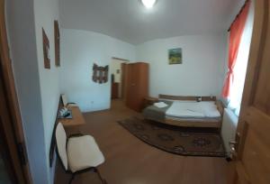Statjunea BorsaにあるPensiunea Mariaのベッド、デスク、椅子が備わる小さな客室です。