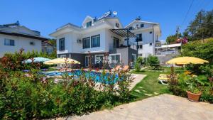 a house with a yard with umbrellas and a pool at Villasunlight in Fethiye