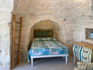 a bedroom with a bed in a stone wall at Trullo Nadia Ostuni in Ostuni