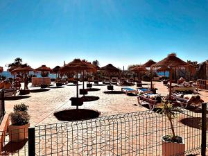 a beach with chairs and umbrellas and the ocean at Apartamentos Sol y Playa Almuñecar 2 in Almuñécar