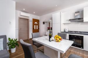 uma cozinha branca com uma mesa e cadeiras brancas em Apartman Palada em Žminj