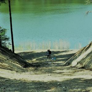 a person riding a bike on a path near the water at EKO Domek u Siemion in Raczki