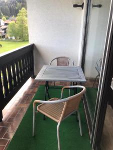 een tafel en stoelen op een balkon met groen tapijt bij Schöne Ferienwohnung im Südschwarzwald in Herrischried