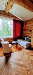 ein Wohnzimmer mit einem Sofa, Stühlen und einem Fenster in der Unterkunft Cozy Log Cabin by Invisible Forest Lodge in Rovaniemi