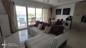 een woonkamer met een witte bank en een keuken bij Aquamarine Sea Front Apartments - Third Floor in Marsaskala