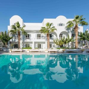 a swimming pool in front of a building with palm trees at Hotel 28 in Kamari