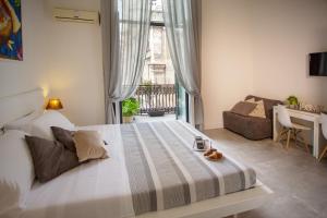 a bedroom with a large bed and a living room at B&B Palazzo Bruca Catania in Catania