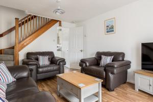 sala de estar con sillas de cuero y TV de pantalla plana en Coast Away, en Poole